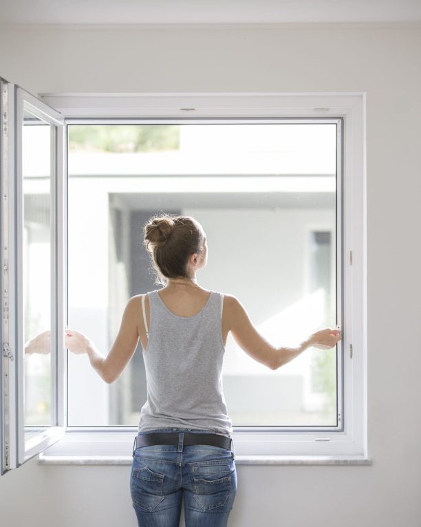 Insektenschutz Spannrahmen am Fenster, Frau öffnet das Fenster