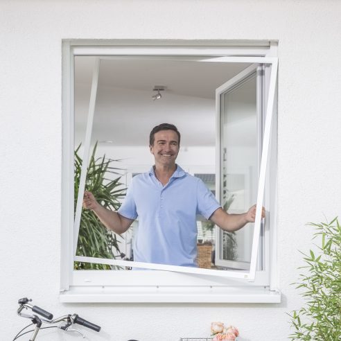 Insektenschutz Spannrahmen am Fenster, Mann öffnet den Spannrahmen